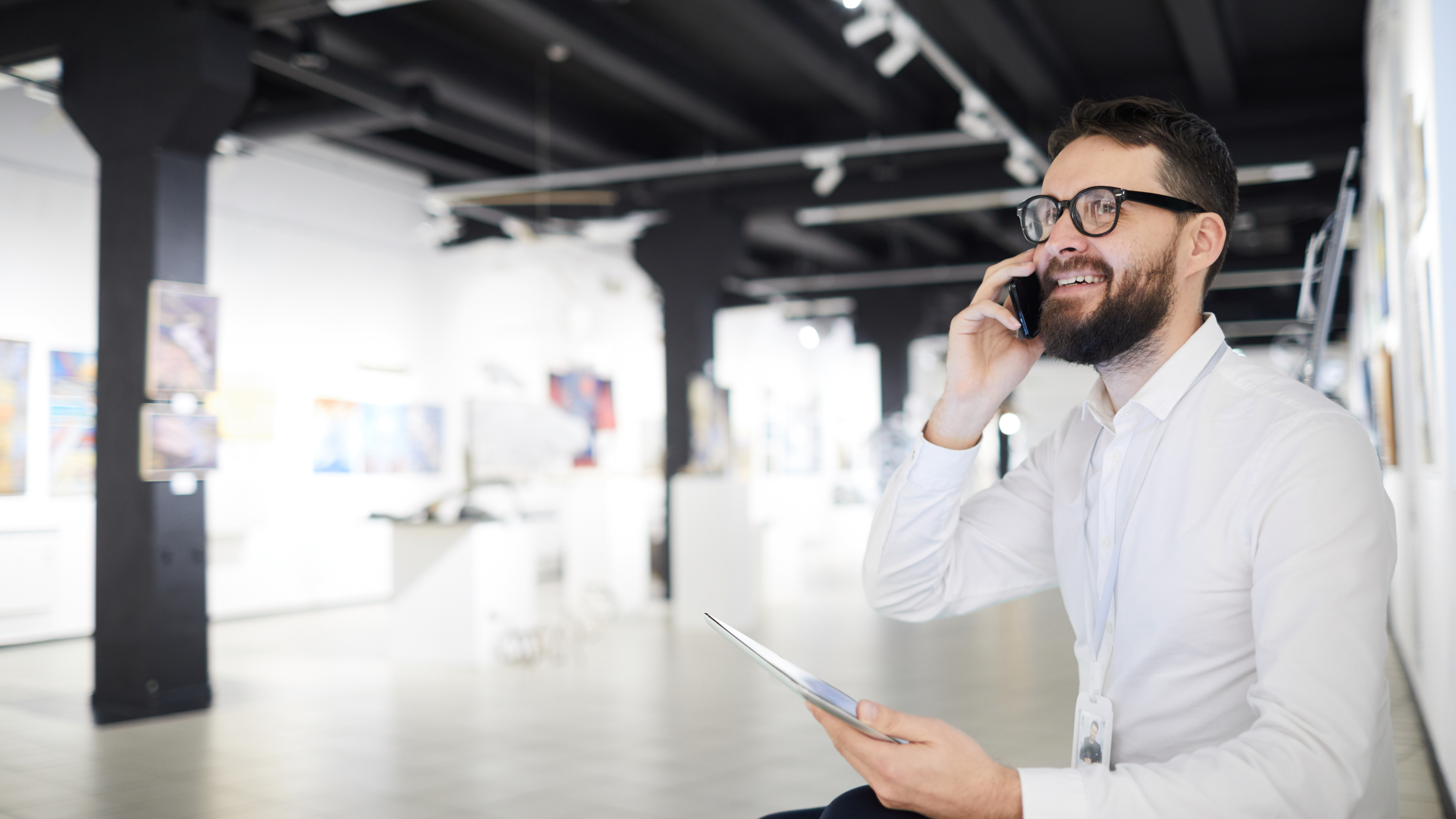 Decorative Image. A gallery manager multitasks using a phone and tablet.